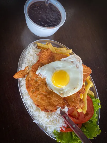 À la minuta de frango à milanesa, com arroz, feijão, fritas, salada e ovo